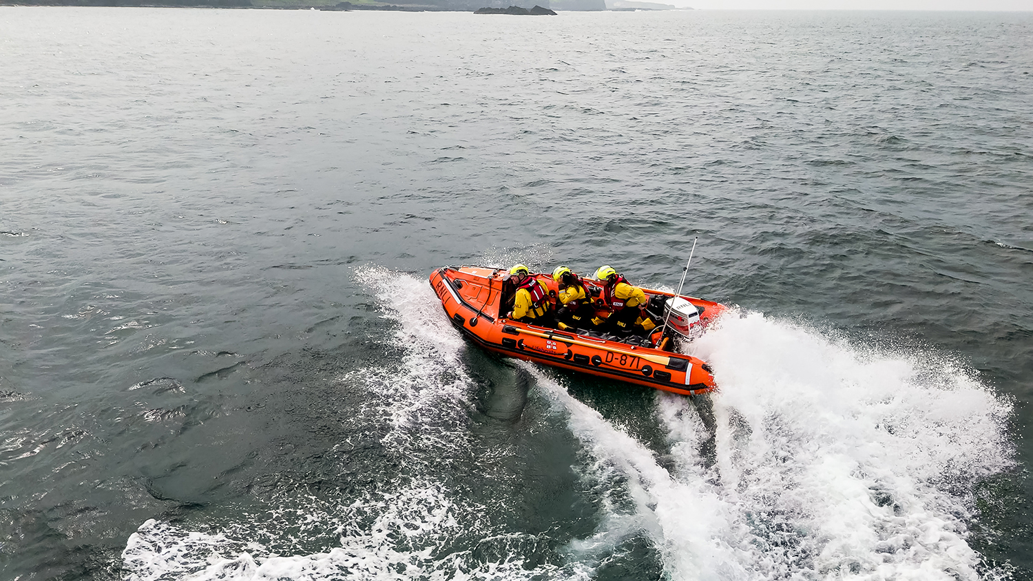 An RNLI crew aboard their D class inshore lifeboat at sea.