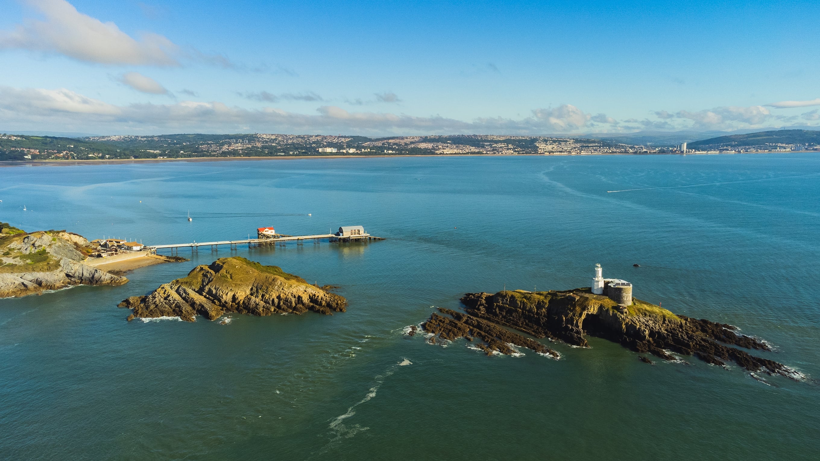 An aerial view of the two islands at Mumbles Head, showing a lighthouse situated on the more remote island. The Mumbles RNLI Lifeboat Station is in the background. Photo: Shutterstock.