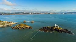An aerial view of the two islands at Mumbles Head, showing a lighthouse situated on the more remote island. The Mumbles RNLI Lifeboat Station is in the background. Photo: Shutterstock.
