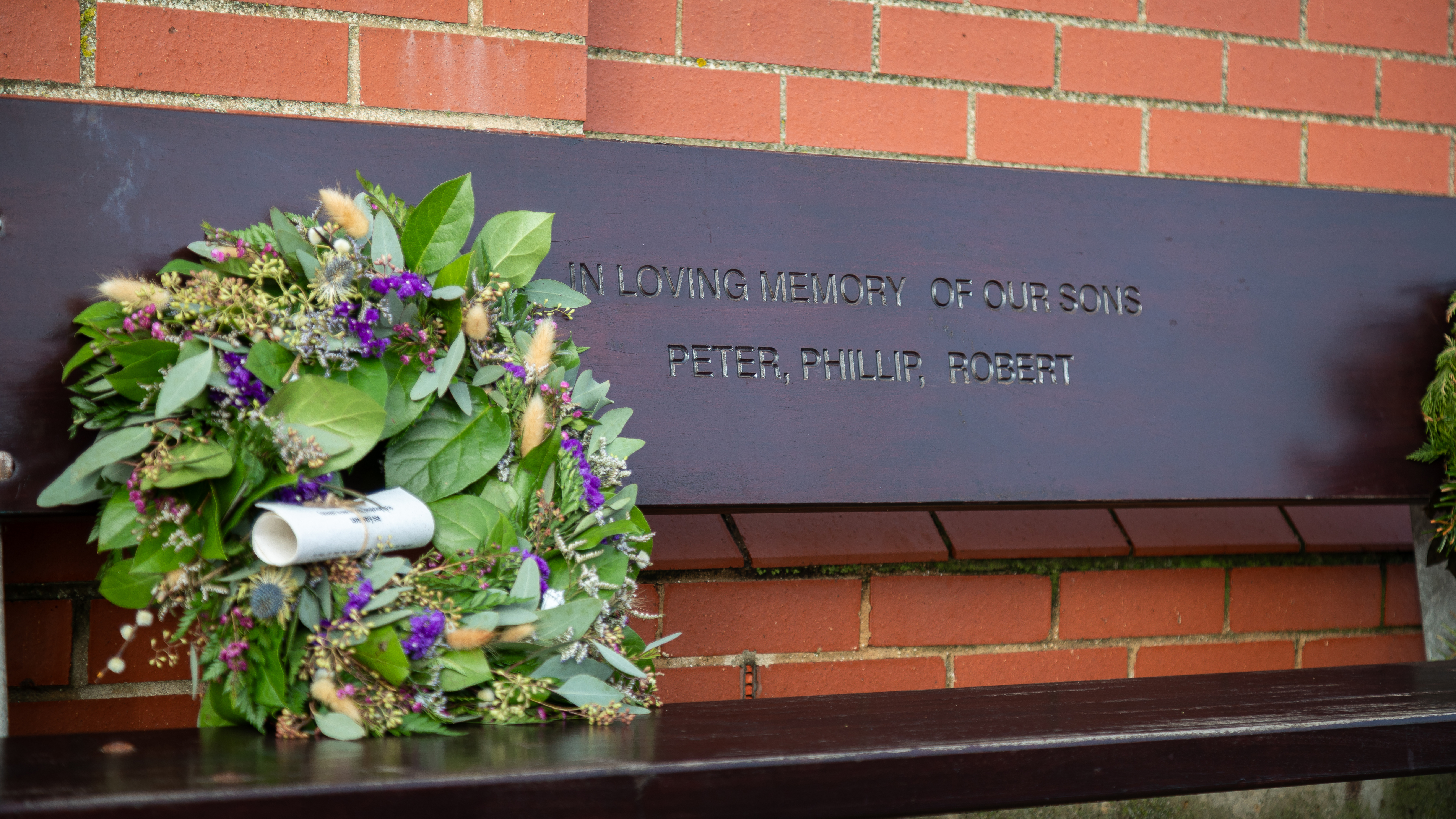 The wreath, with green leaves, purple flowers and a scroll attached, rests on a commemorative bench in Pete’s memory. 