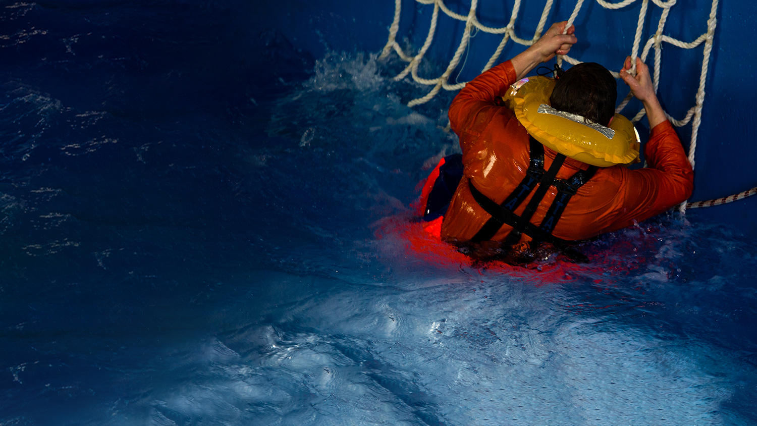 Man wearing lifejacket climbing up a recovery net