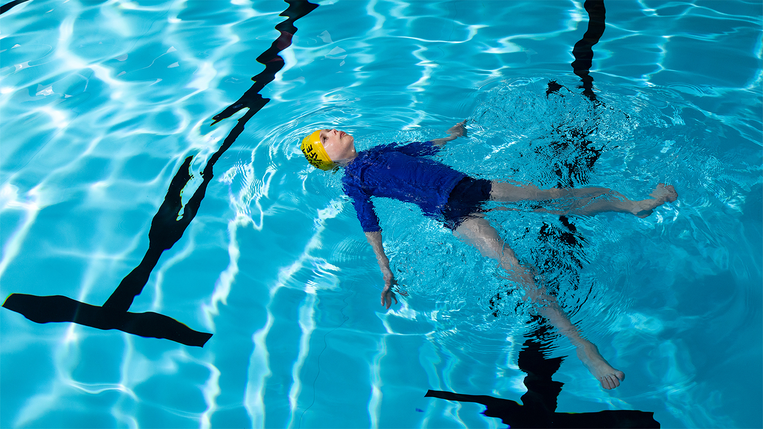 Child floating on their back in a swimming pool