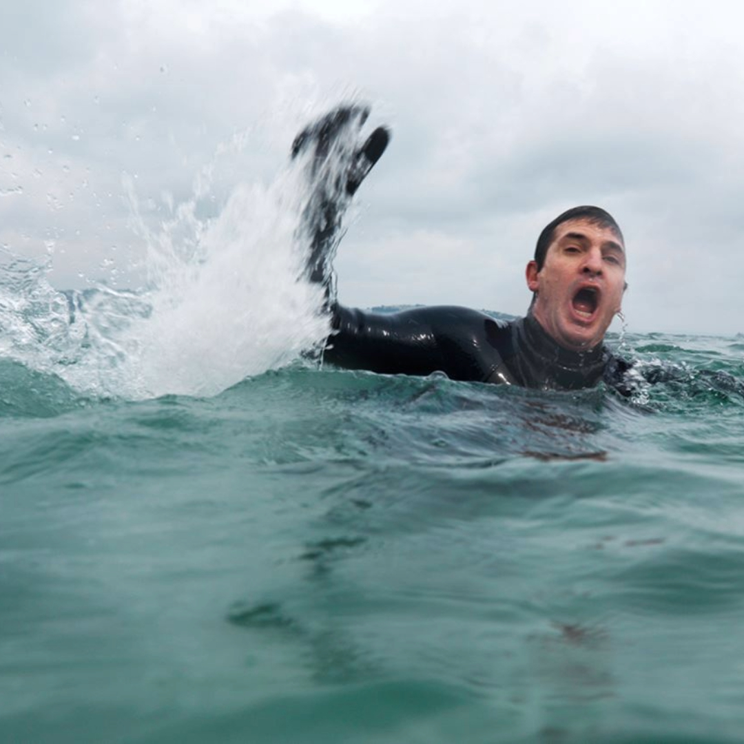 Simulation of a man drowning incident. Casualty is waving to lifeguards for help.