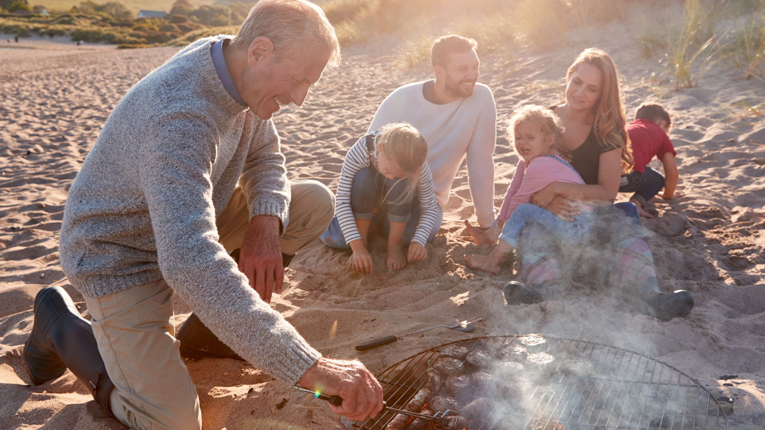 A family cooking food on a BBQ on the beach