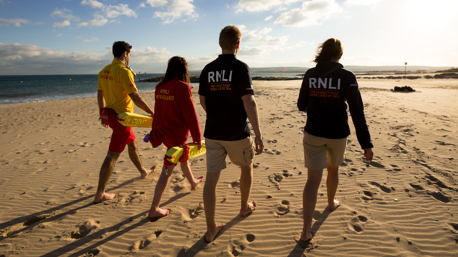 Lifeguards and face to face fundraisers walking barefoot along a beach