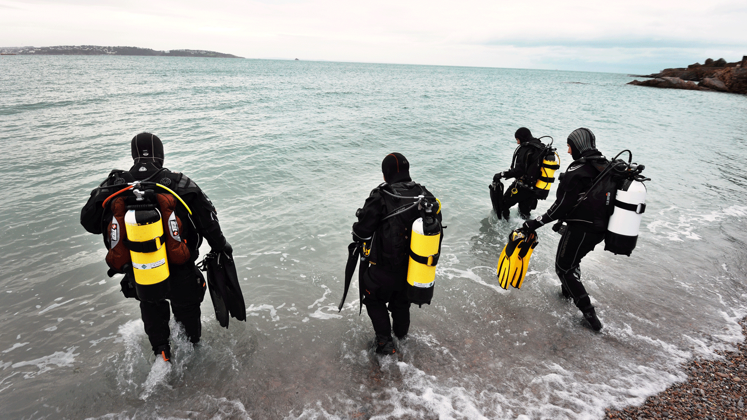 A group of divers walking into the sea 
