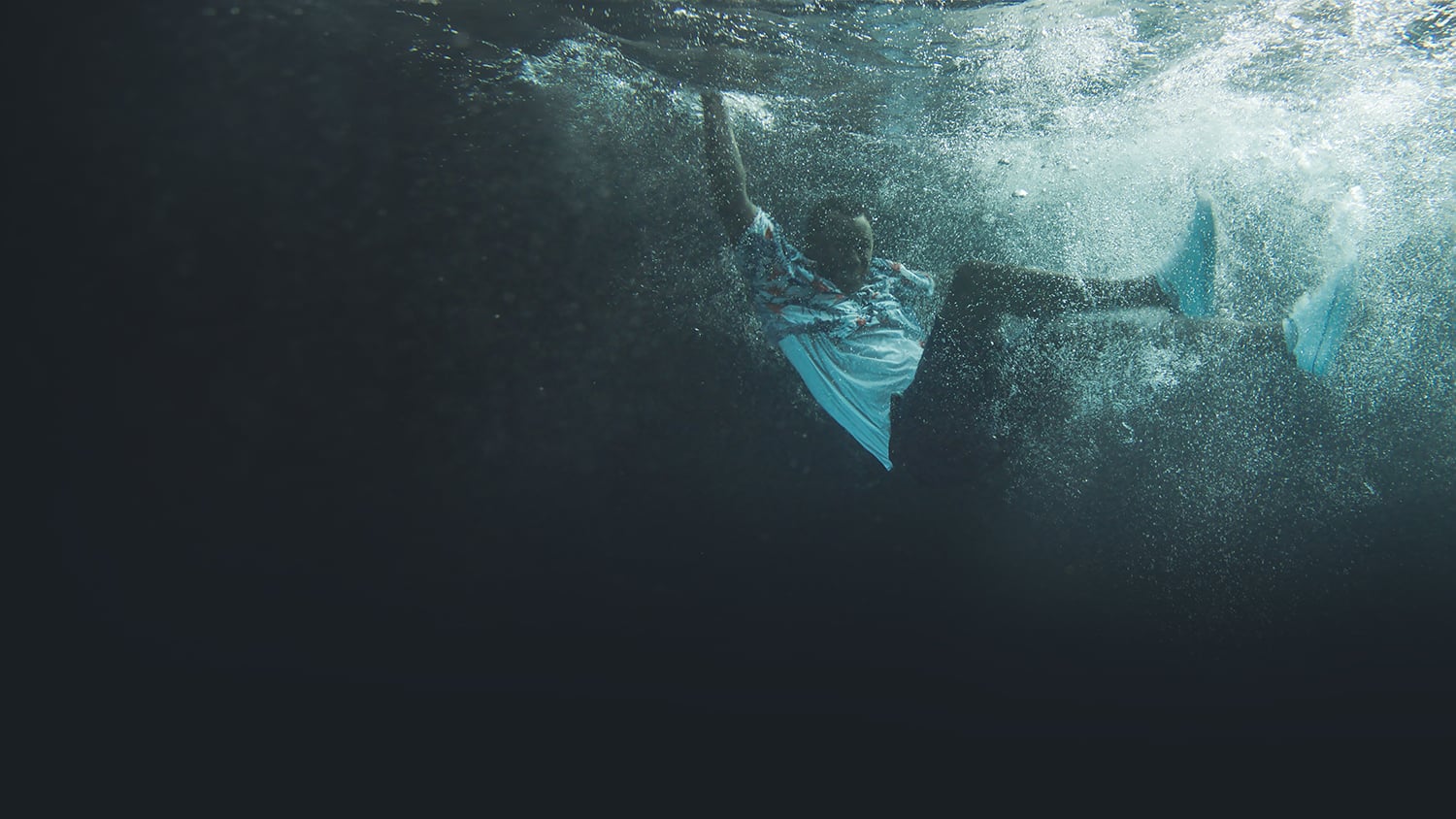 A fully-clothed man underwater after falling into the water
