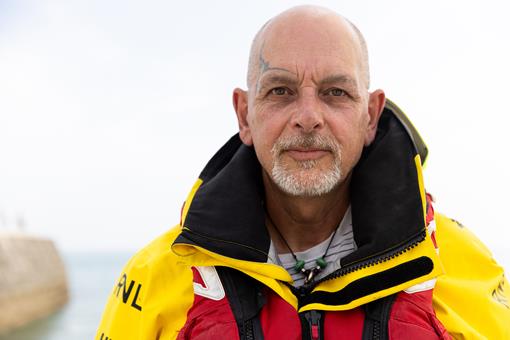 Portrait of Mike Chant, RNLI mechanic and crew member, in yellow crew kit.