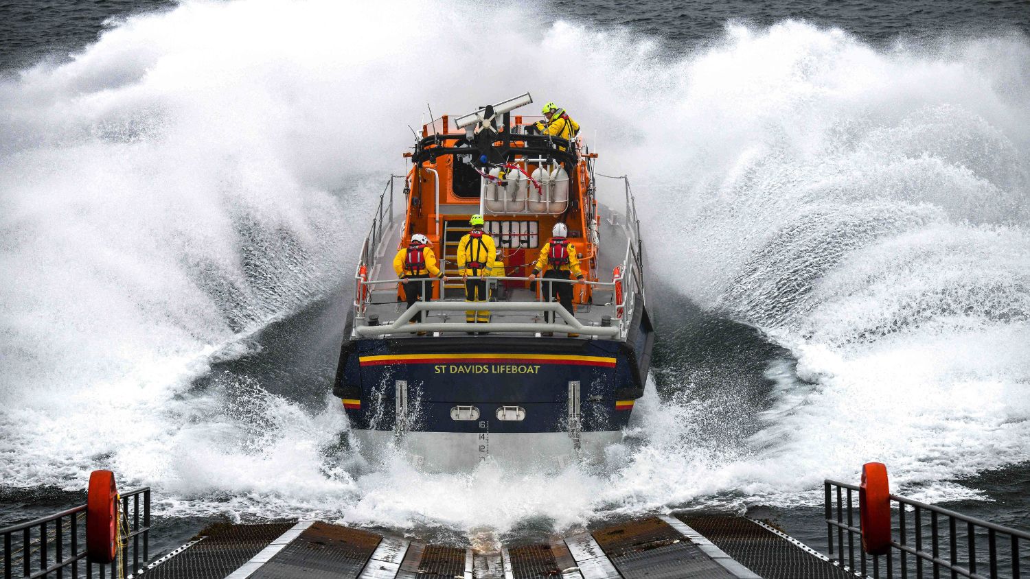 St Davids lifeboat station’s Tamar class all-weather lifeboat launches from the slipway into seas creating a huge splash as it enters the water