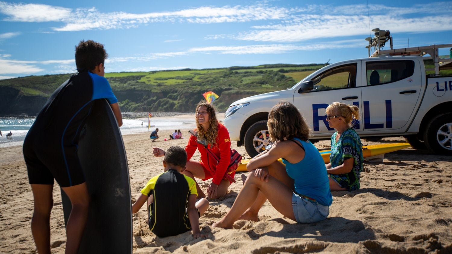 Lifeguards sitting on a beach with member of the public sharing safety advice