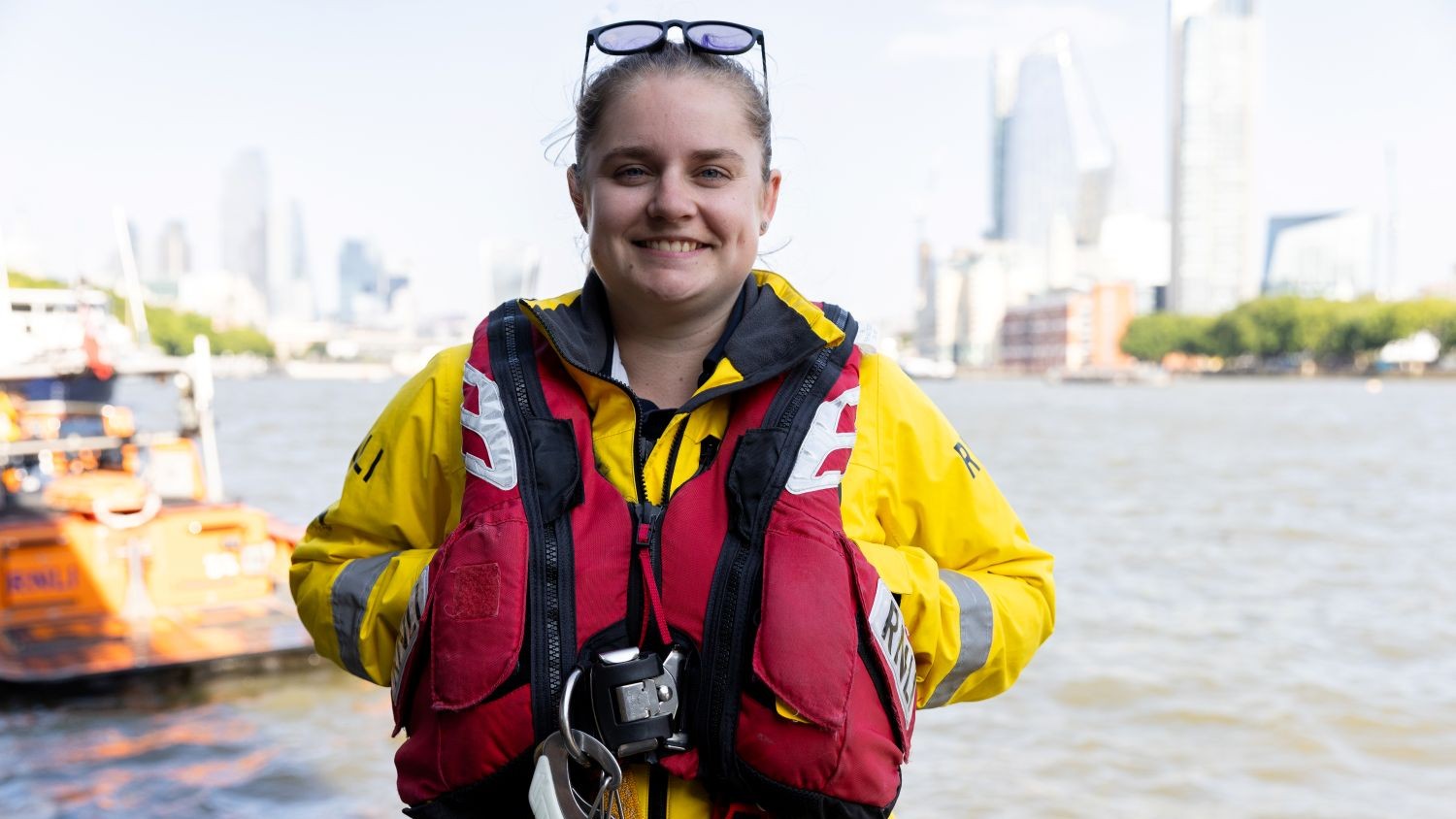 Portrait shot of Thames Volunteer Crew Member and RNLI Technician Stephanie Bigsby in crew kit with the River Thames in the background.