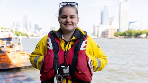 Portrait shot of Thames Volunteer Crew Member and RNLI Technician Stephanie Bigsby in crew kit with the River Thames in the background.