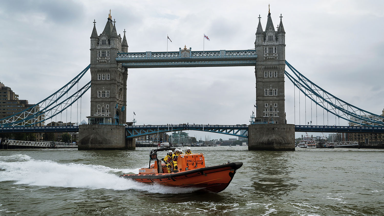 Tower lifeboat crew on the River Thames in an E class lifeboat with Tower Bridge in the background.