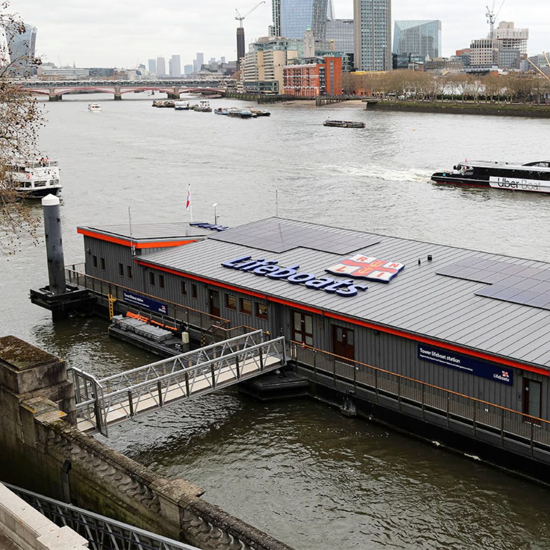 Tower Lifeboat Station on the River Thames with traffic on the river and Blackfriars Bridge and the iconic London cityscape in the background.