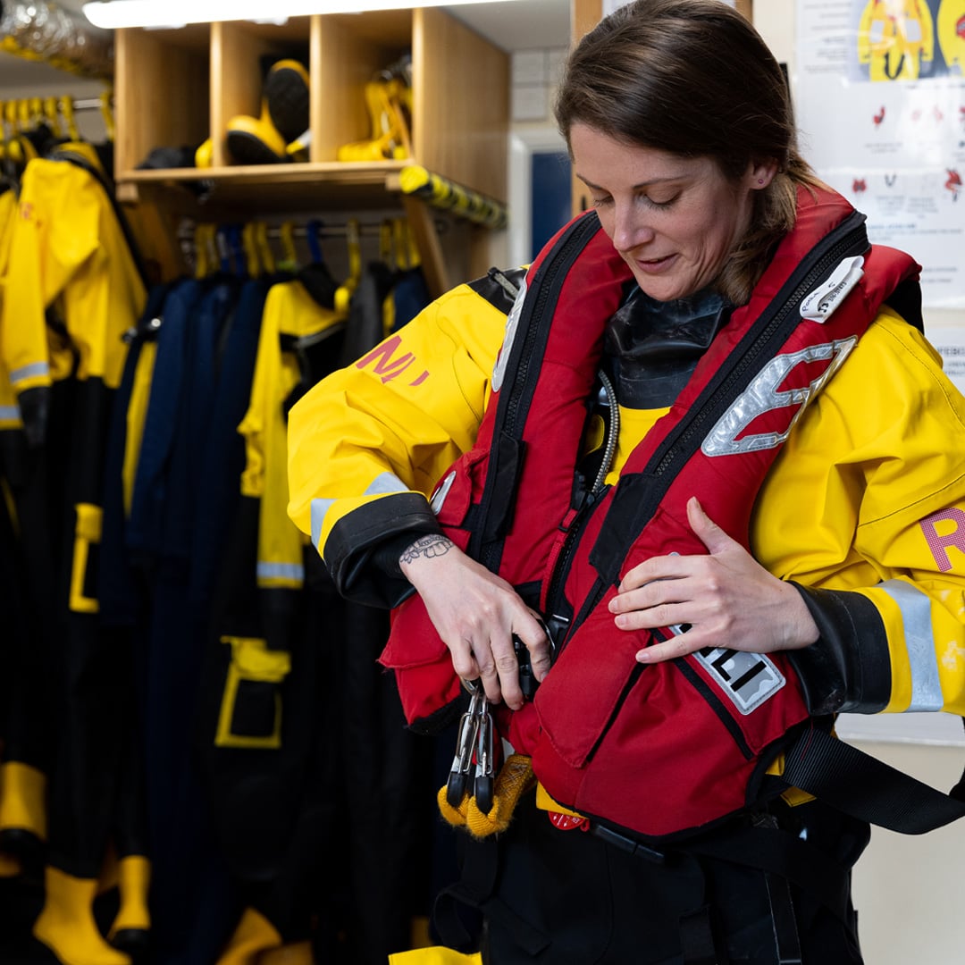 An RNLI crew member putting on a life vest. 
