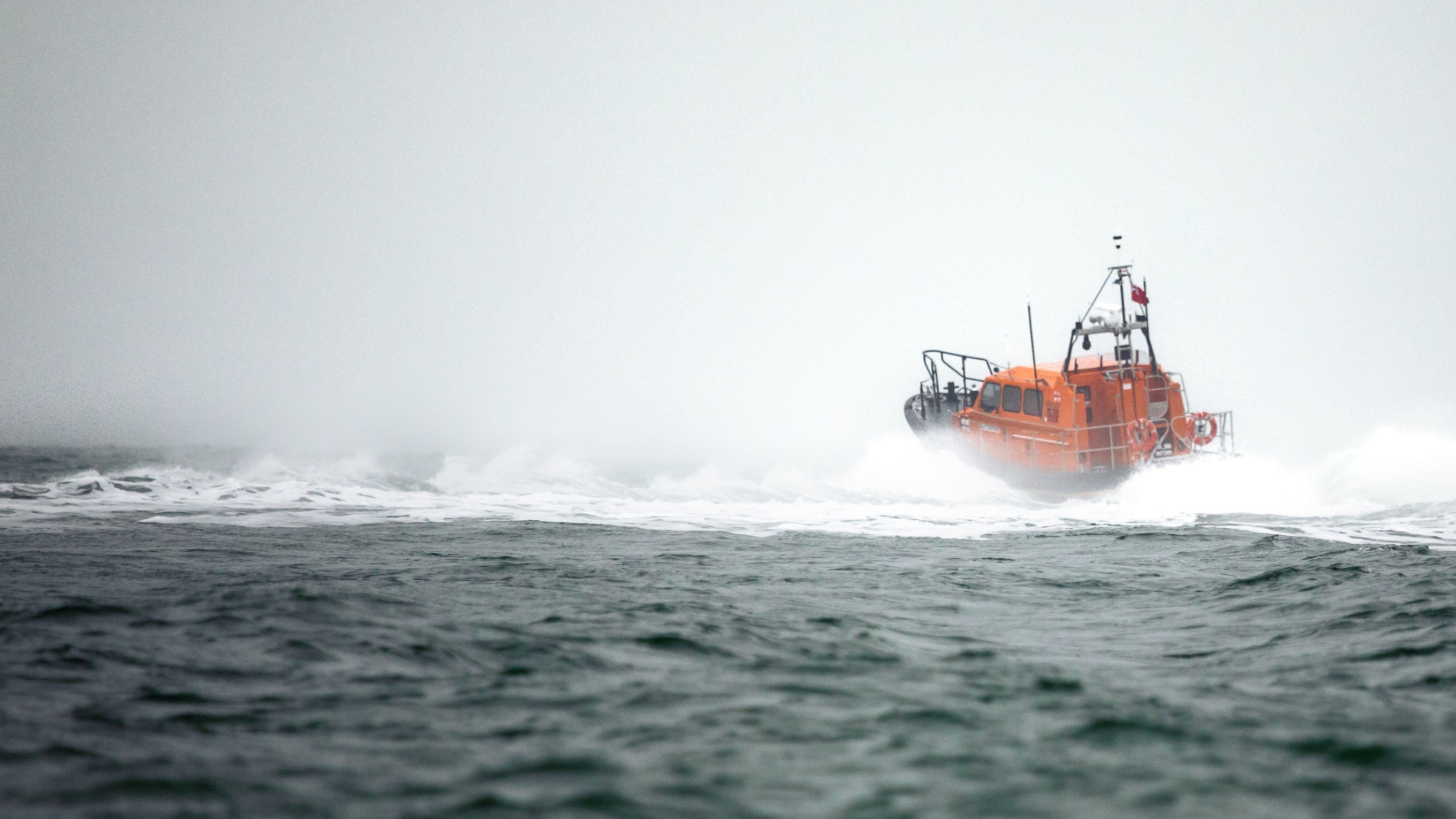 An RNLI Shannon class all-weather lifeboat powers away from us in rough seas