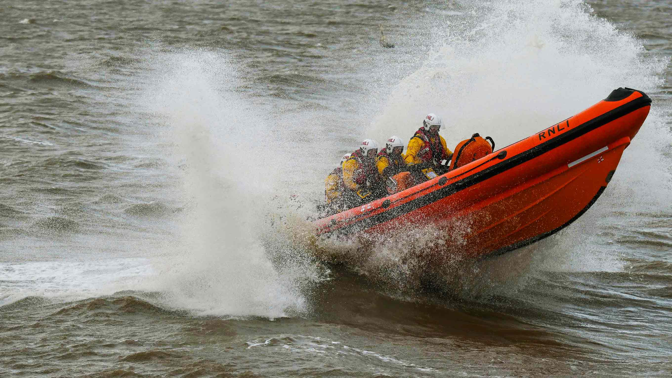 Whitstable's B class lifeboat flies from the crest of a wave as it navigates grey stormy seas