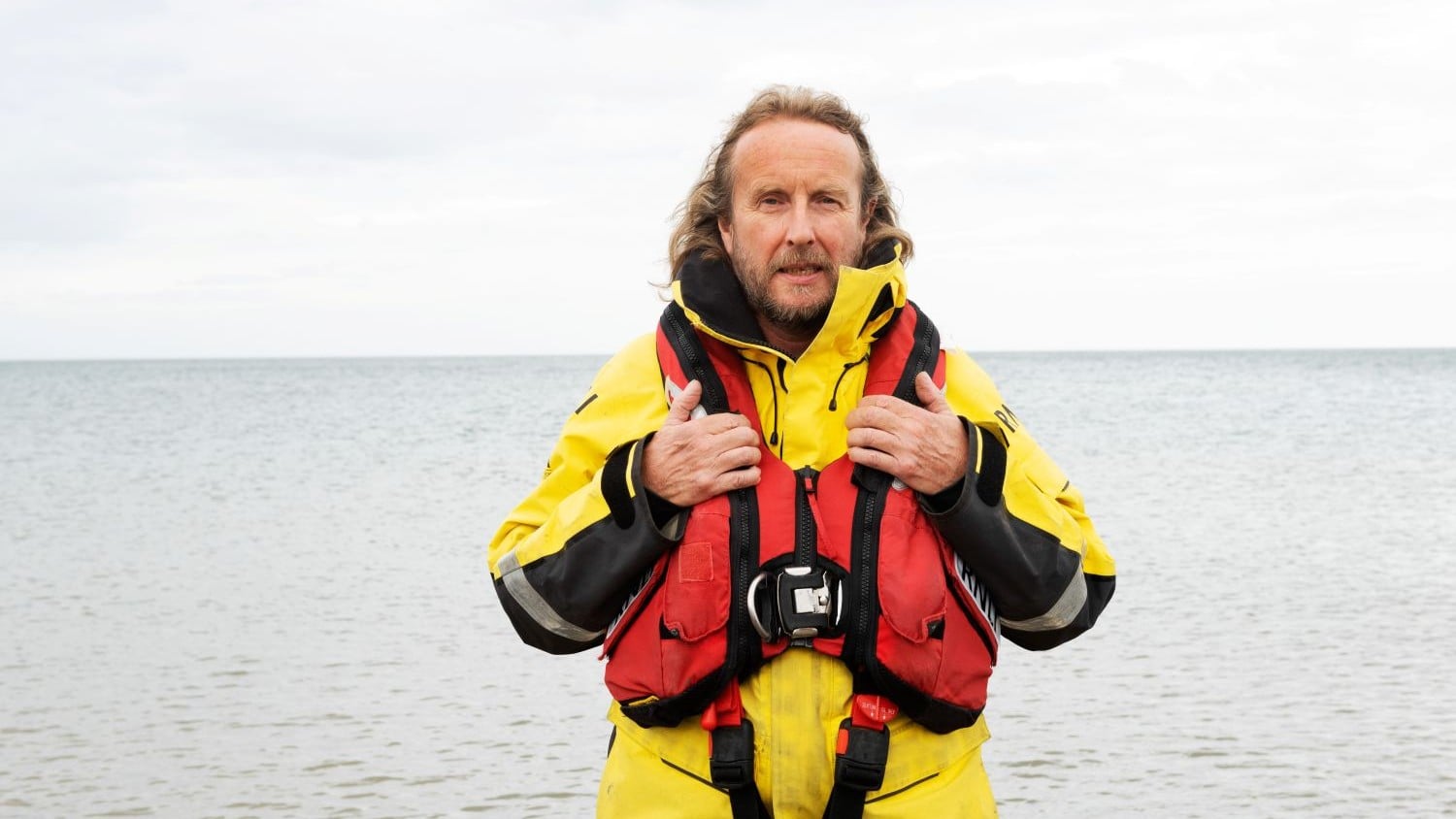 Volunteer Llandudno Coxswain Graham Heritage standing by the sea in his kit.