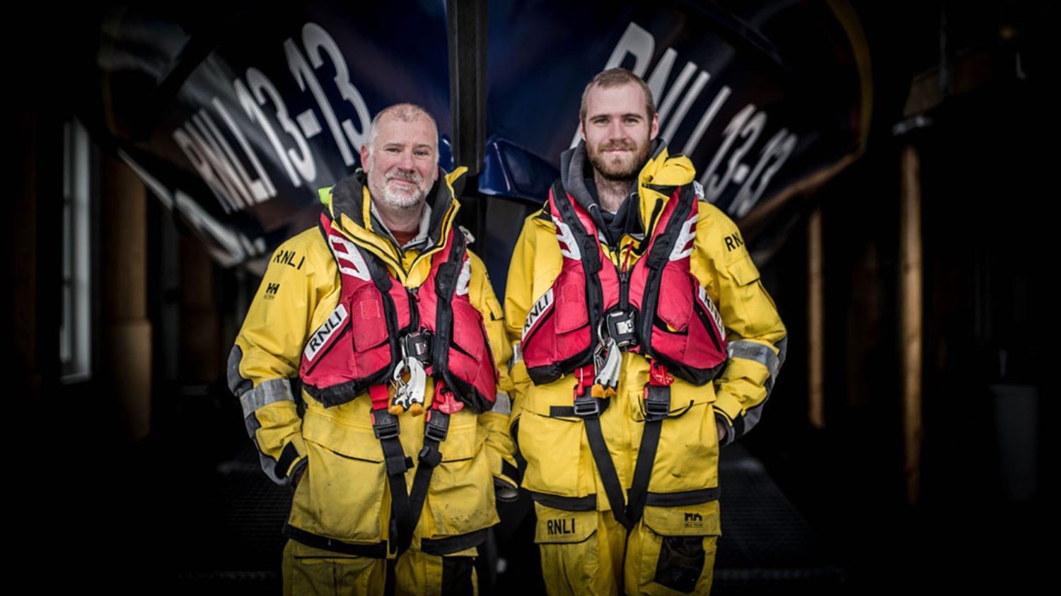 Steve and Felix Williams in front of Swanage RNLI lifeboat RNLI 13-13, showcasing crew legacy and volunteer dedication.