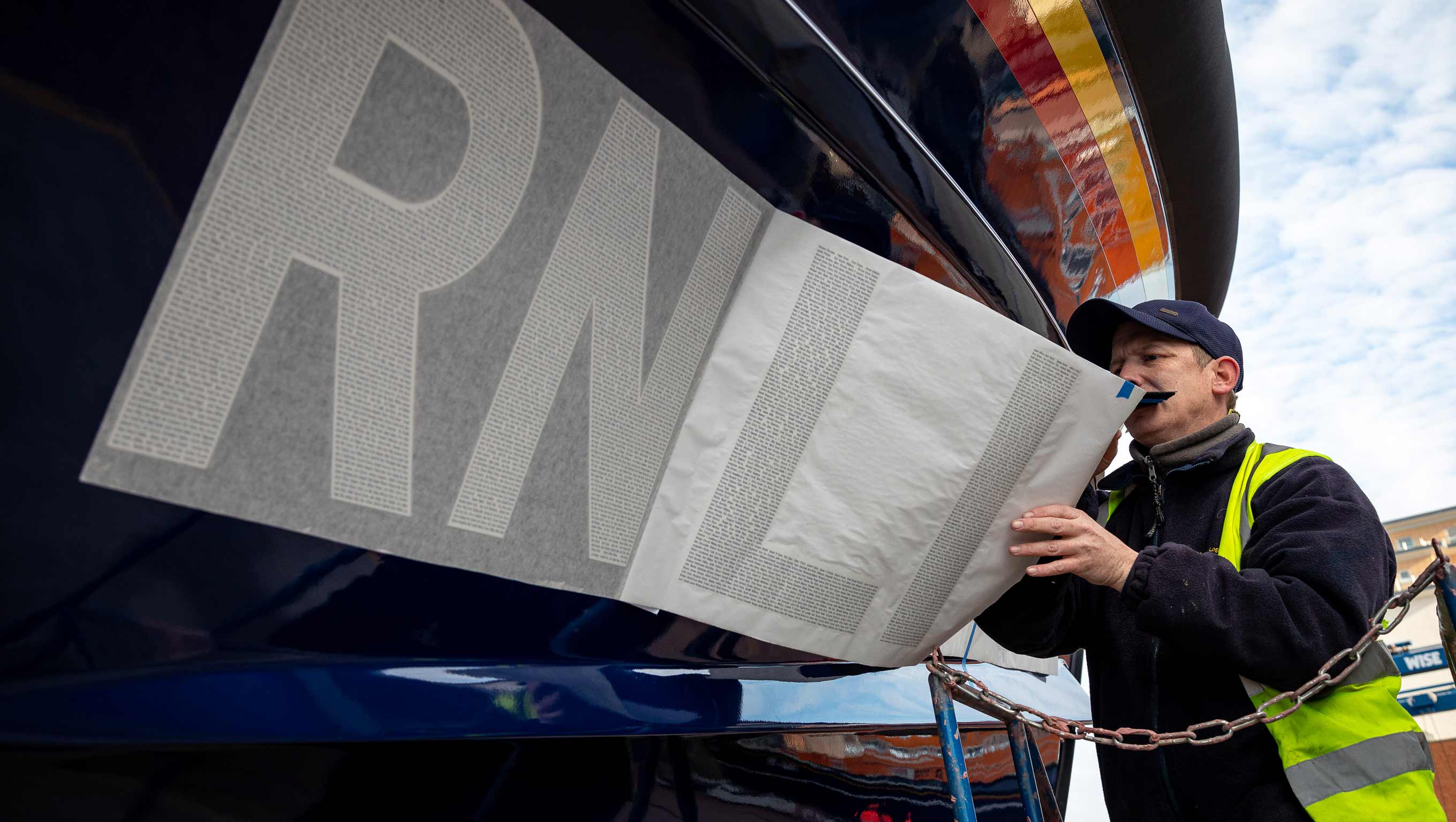 A decal with a serial number including the names of loved ones being applied to the hull of a Shannon class lifeboat.