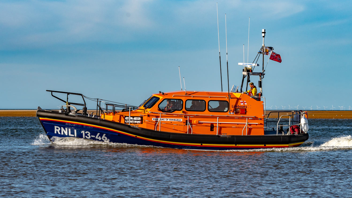 Wells Shannon Class Launch a Memory lifeboat Duke of Edinburgh cruises along the sea on a bright, calm day. 
