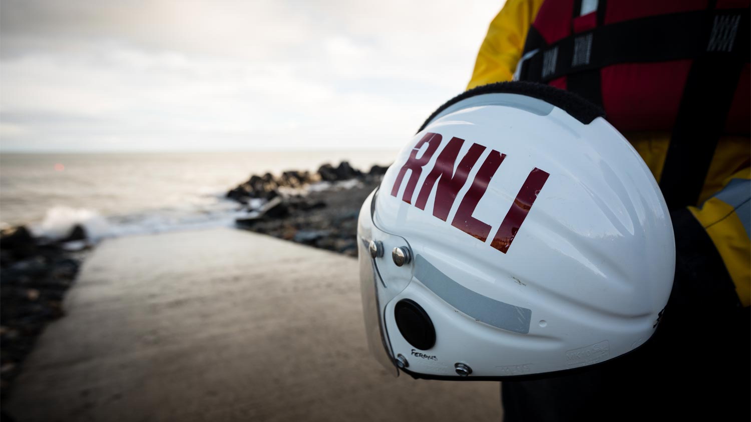 A white lifeboat crew helmet with RNLI printed on it in red letters