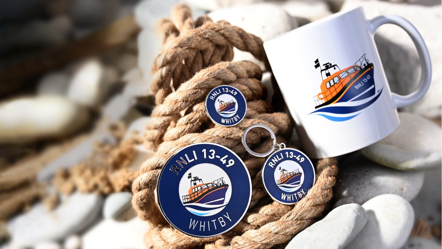 Whitby’s range of high-quality, affordable products resting on a backdrop of pebbles and a coiled rope. Mementos that show the Whitby illustration of the boat and number