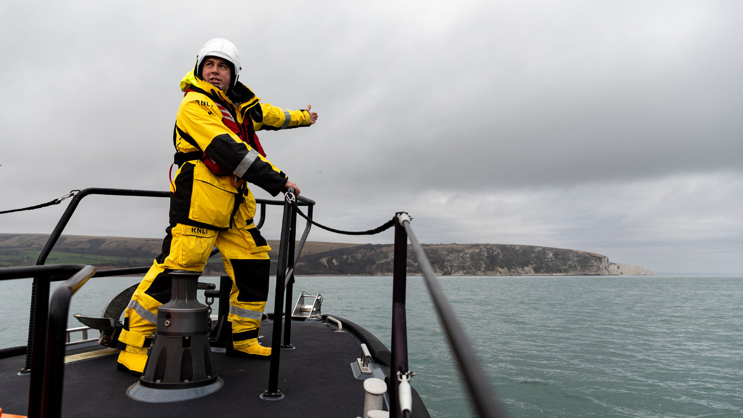 A Swanage RNLI crew member on the deck of a Shannon class lifeboat, pointing ahead