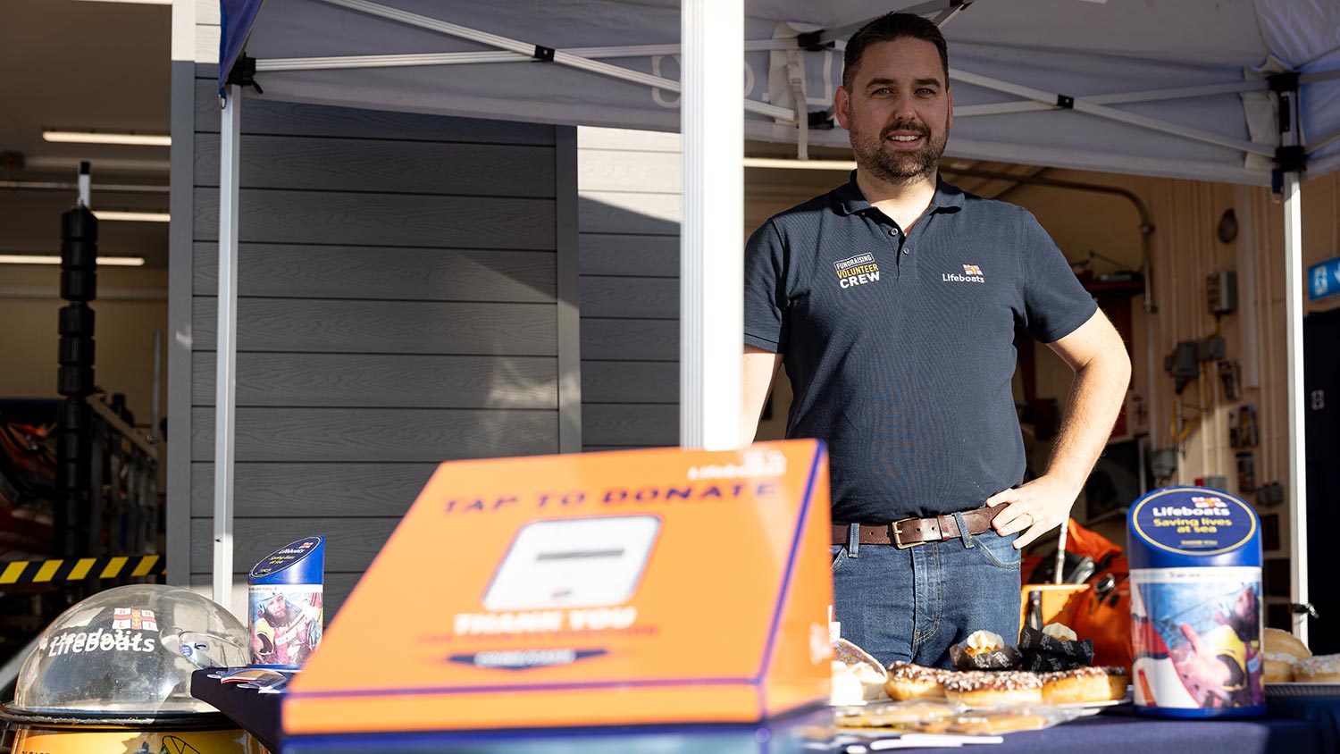 An RNLI fundraiser standing behind a contactless payment machine