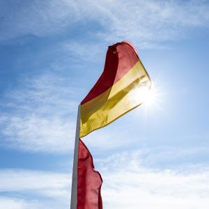 Red and yellow lifeguard flag blowing in the wind.