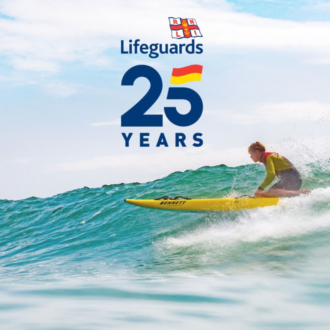 A lifeguard sits on a rescue board on a wave under the words Lifeguard 25.