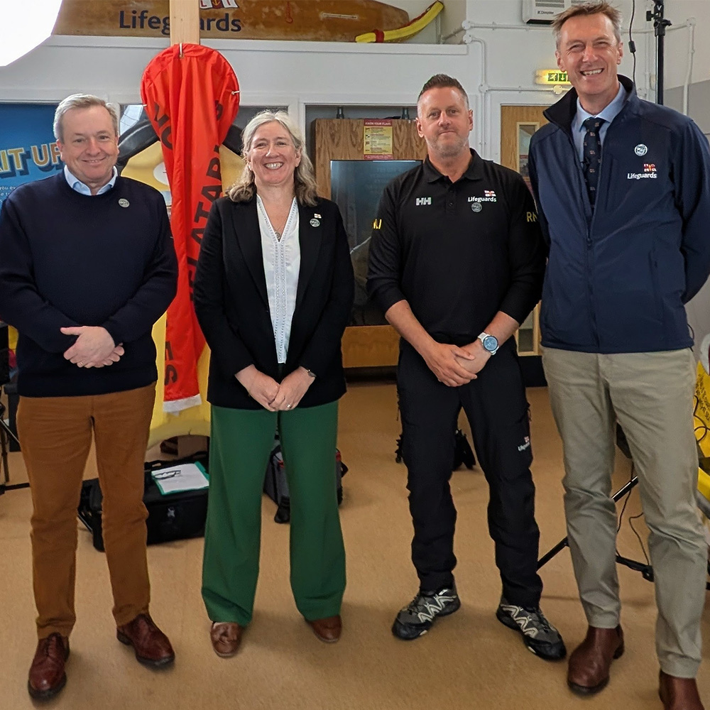 Four people standing and smiling inside a Lifeguard Visitor Centre.