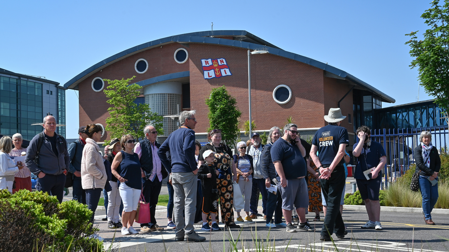 A group of RNLI visits volunteers speaking to members of the public outside the RNLI Sea Survival Centre in Poole.
