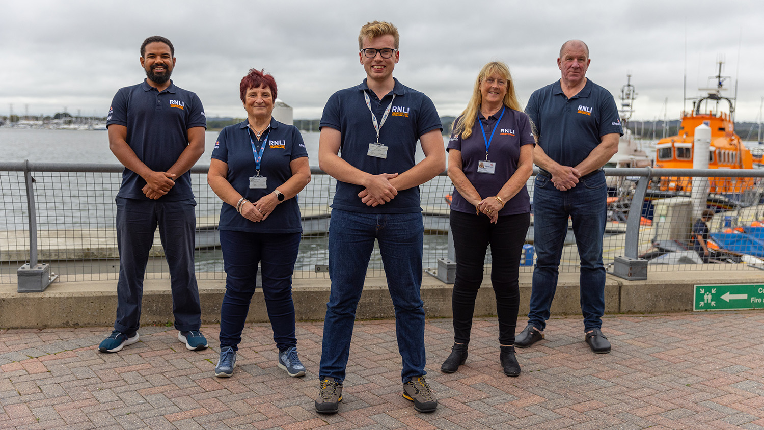 A group of RNLI volunteers stood on the pavement outside the RNLI College in Poole.