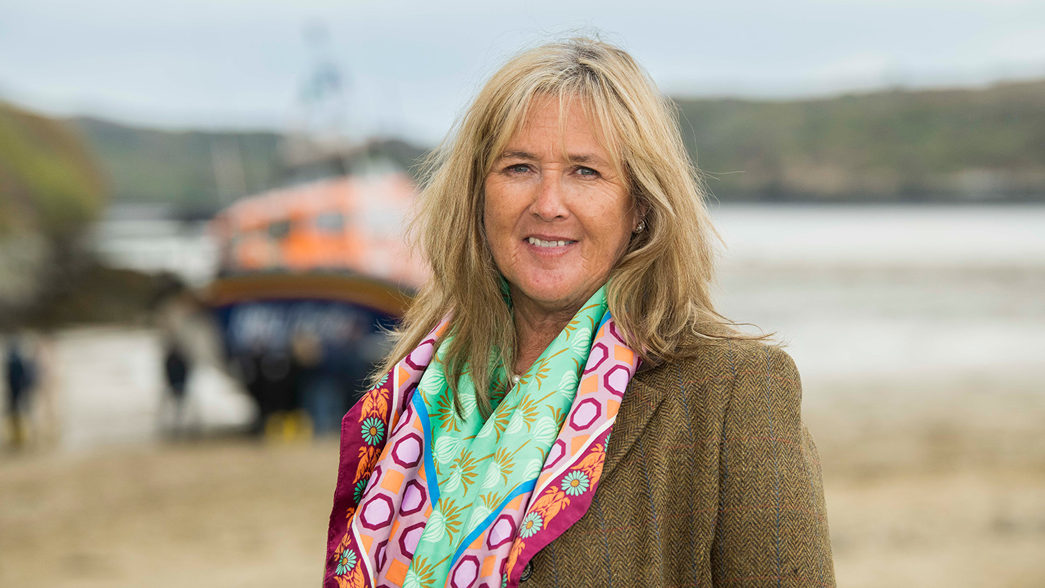 Anna Classon standing and smiling on a beach in front of an RNLI lifeboat.
