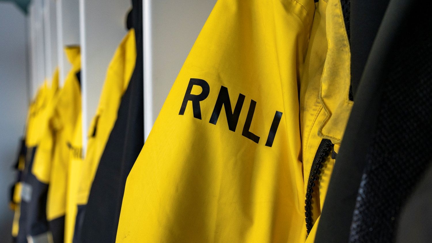 A row of yellow RNLI lifeboat kit hanging up
