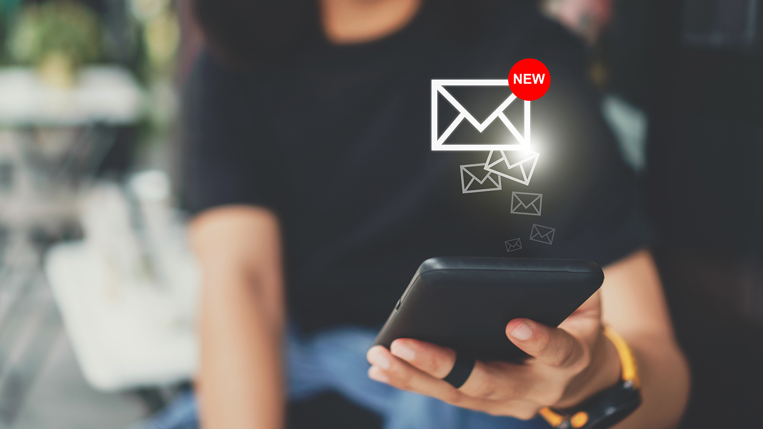 A person checking a mobile device, which as new email icons above.