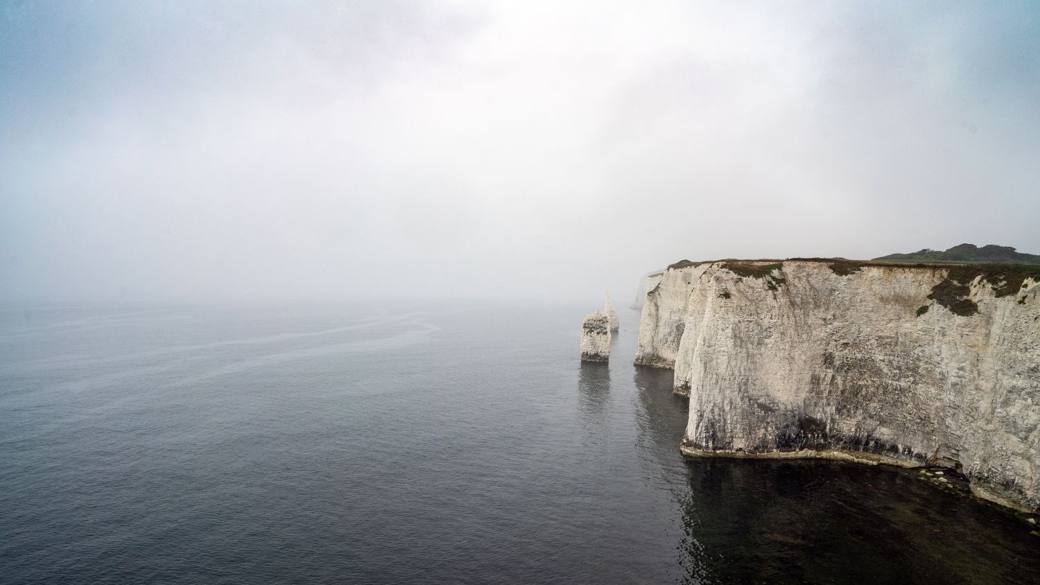 View of Old Harry Rocks against calm sea and cloudy sky