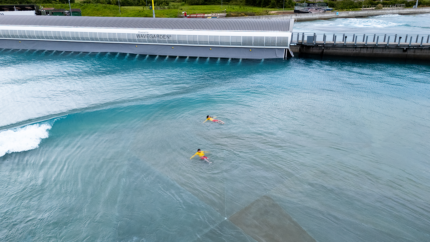 Two RNLI lifeguards in uniform floating on their backs in an artificial wave pool.