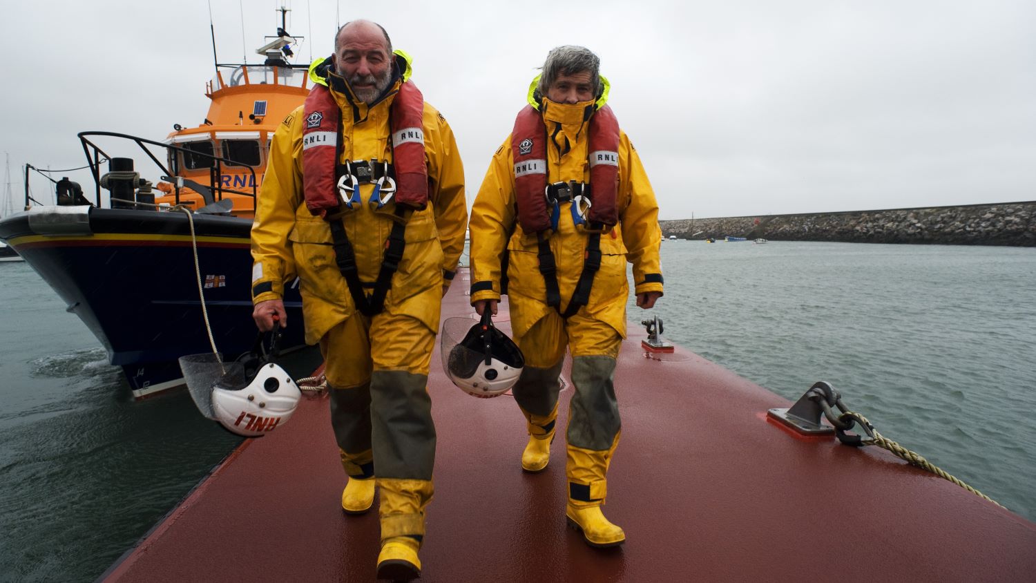 Torbay Crew Members John Ashford and Richard Fowler walking down the original pontoon with their Severn class lifeboat, Alec and Christina Dykes 17-28, in the background