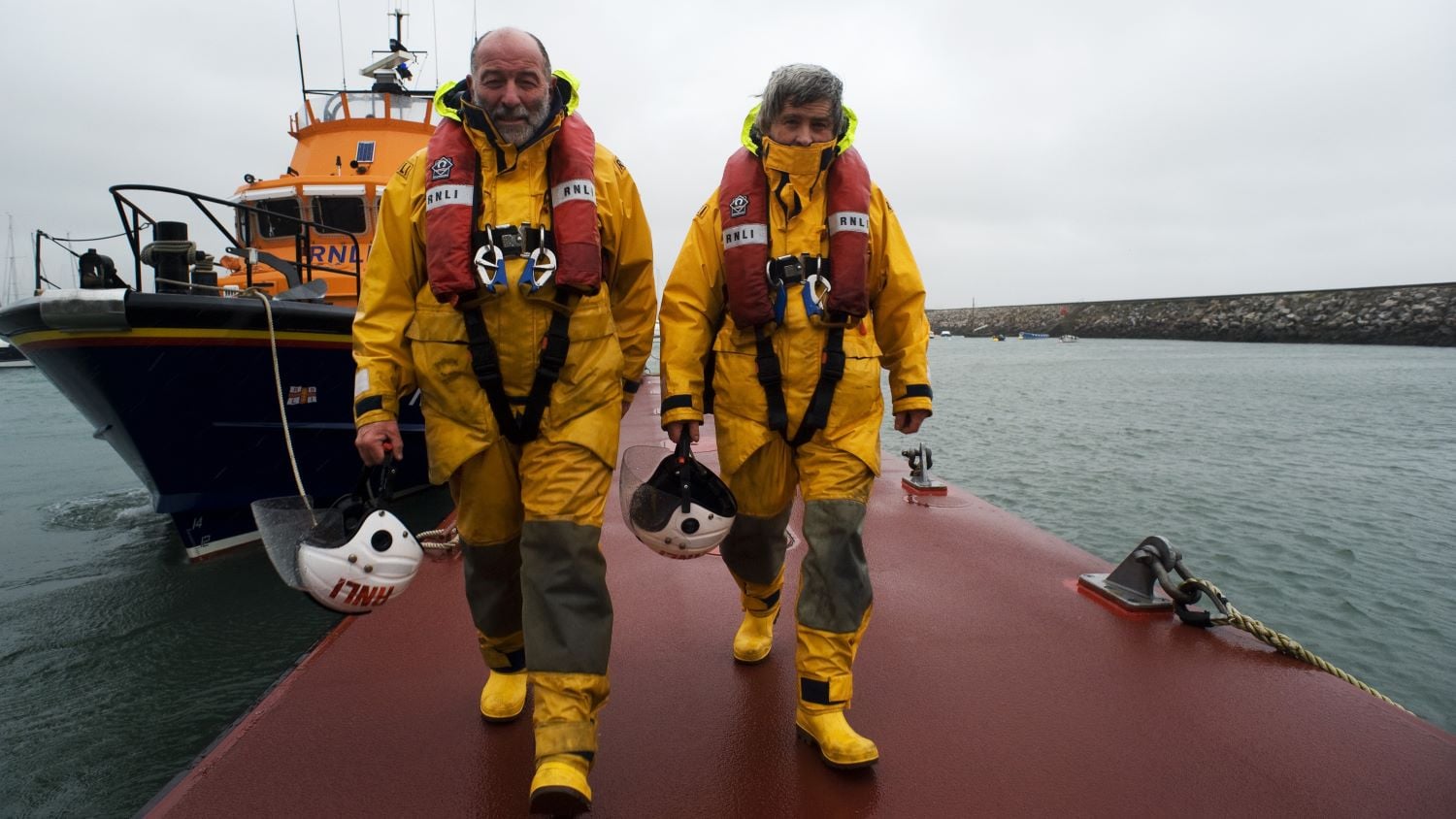 Torbay Crew Members John Ashford and Richard Fowler walking down the original pontoon with their Severn class lifeboat, Alec and Christina Dykes 17-28, in the background
