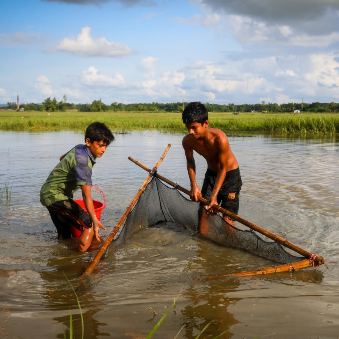 Faisal (11) and Jamal (18) fish on the floodwaters after a monsoon. Cox s Bazar. Bangladesh. One inch of water international project.
