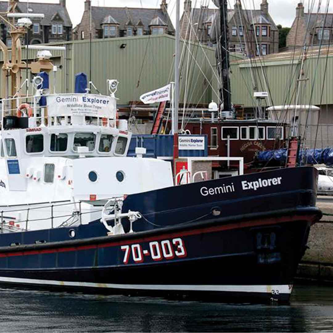 A retired Clyde class all-weather lifeboat sits moored in a harbour. It has been repainted white.
