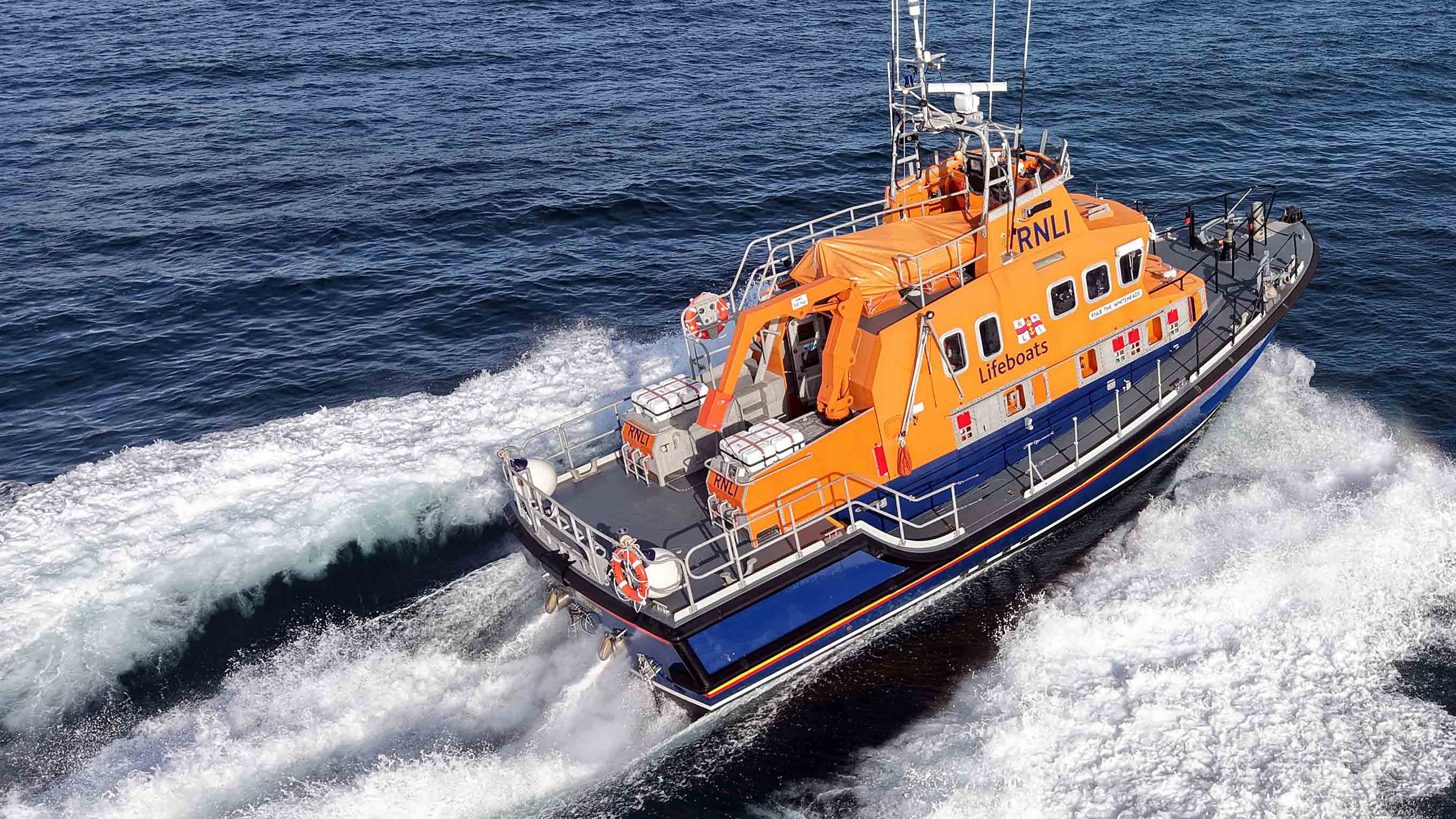 Severn class all-weather lifeboat cruises across calm blue seas in bright sunshine