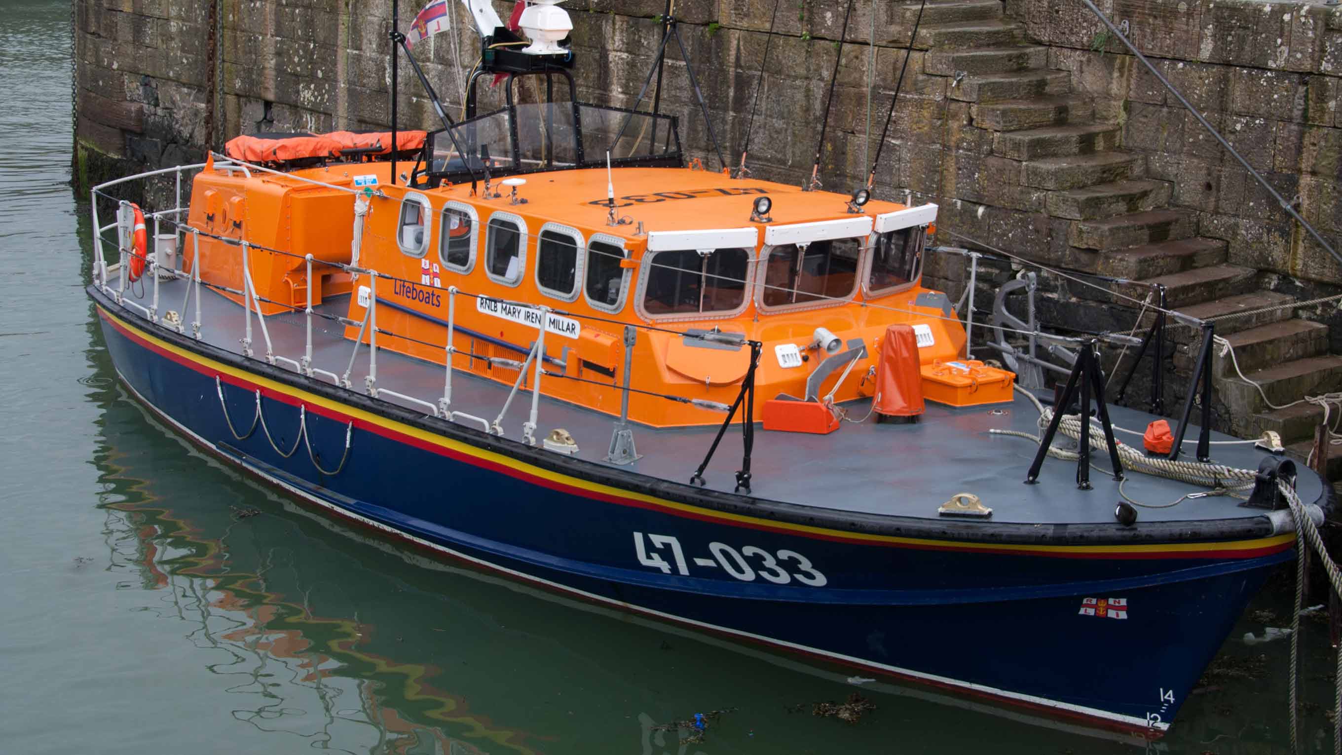 A Tyne class all-weather lifeboat sits moored in the harbour at the quayside. 