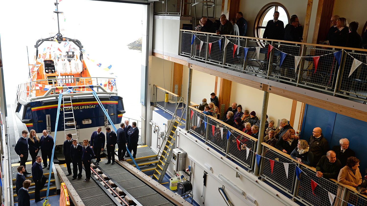 People are gathered inside the new boathouse and the Tamar class lifeboat is on the slipway.