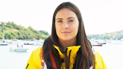 Crew Member Tegan Flage, standing in front of the water in her RNLI kit. Credit: RNLI/Nigel Millard